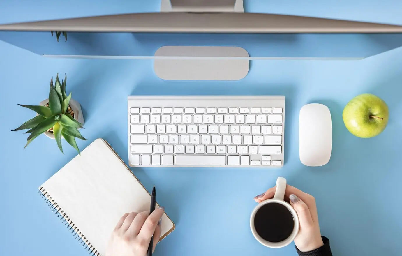 Ansicht von oben: Weibliche Hände arbeiten am Computer vor blauem Hintergrund.